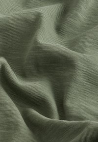 Maslinasto zelena pletena tkanina s teksturiranom površinom, s finim rebrastim uzorkom i glatkim padom, prikazujući mekanu, srednje tešku konstrukciju.