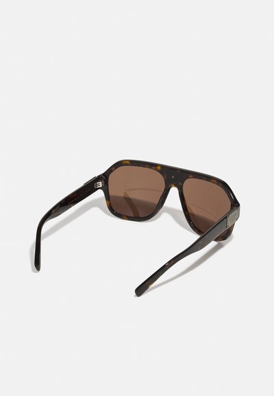 Ochelari de soare cu nuanță maro, cu un cadru din scoică de țestoasă, design unghiular și accente negre elegante pe timbre.