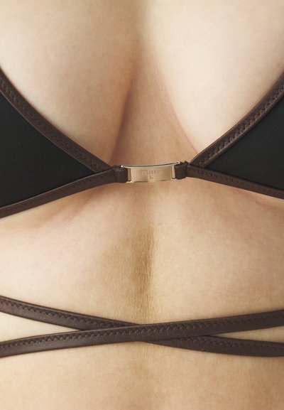 Black bikini top with brown trim, featuring a rectangular silver clasp at the center back. Straps cross at the back, creating an X shape.