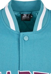 Col de veste varsity bleu sarcelle avec des rayures blanches, un bouton-pression et une étiquette noire Starter Black Label à l'intérieur de l'encolure.