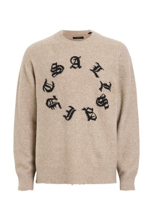 Beige wollen sweater met ronde hals, voorzien van zwarte letters in een cirkelpatroon. De tekst ziet er verouderd uit, met ribbels aan de manchetten en de onderkant.