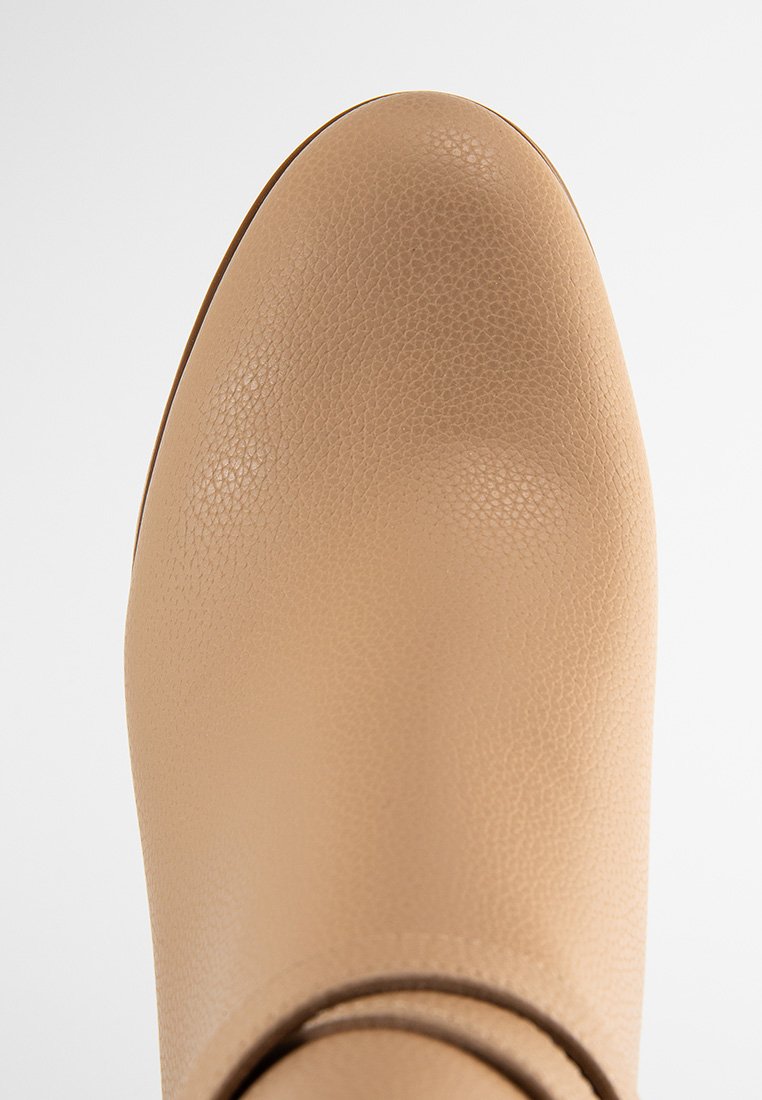 Beige Knöchelstiefel aus strukturiertem Leder mit runder Spitze und minimalistischem Design. Keine sichtbaren Beschläge oder Akzente. Glatte Oberfläche.