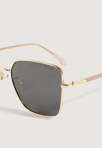 Gafas de sol cuadradas con montura de metal dorado y lentes oscuros, con el logo de Polaroid en la lente y en la pata.