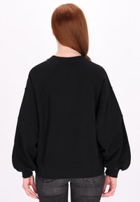 Czarna, oversize bluza z raglanowymi rękawami, ściągaczem przy kołnierzu i mankietach, z gładką fakturą i luźnym krojem.