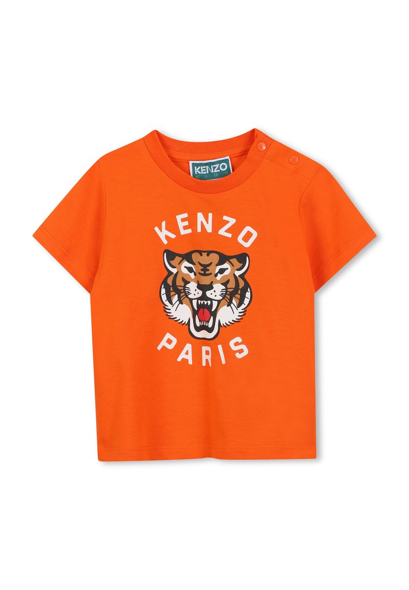 T-shirt en coton orange avec un graphisme de tigre et le texte "KENZO PARIS". Manches courtes avec deux boutons-pression à l'épaule pour un habillage facile.
