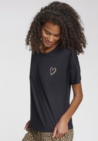 Schwarzes T-Shirt aus weichem Stoff, mit kurzen Ärmeln und einem Leopardenherz-Print auf der linken Brust. Gerader Schnitt und lässige Passform.