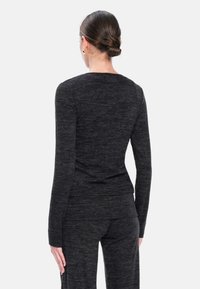 Maglia a maniche lunghe grigia scura in un morbido tessuto a maglia, caratterizzata da un collo rotondo e una silhouette aderente con una texture liscia.