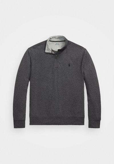 Temno siva pulover majica z majhnim zadrgo pri ovratniku, mehko teksturo in kontrastnim notranjim ovratnikom. Ima majhen vezen logotip na prsih.