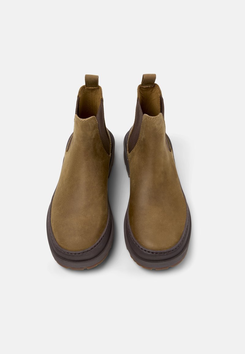 Botas de tobillo de ante marrón con paneles laterales de elasticidad, punta redondeada y suela de goma gruesa. Incluyen lengüetas para facilitar el calzado.