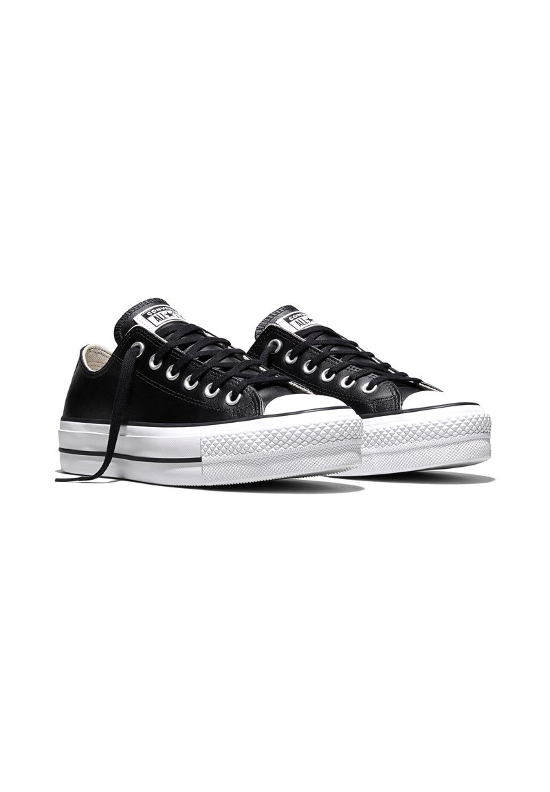 Paar schwarze Low-Top Converse All Star Sneaker mit weißen Gummisohlen und schwarzen Schnürsenkeln auf weißem Hintergrund.