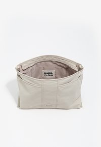 Beżowa torba na ramię o gładkiej, miękkiej fakturze. Posiada zamek błyskawiczny z góry, wewnętrzną metkę oraz zaokrąglone szwy. Przestronna wnętrze.