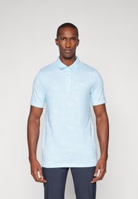Hellblaues Poloshirt aus weichem Stoff, mit einem dezenten Muster und einem knöpfbaren Kragen. Kurzärmlig und figurnah geschnitten.