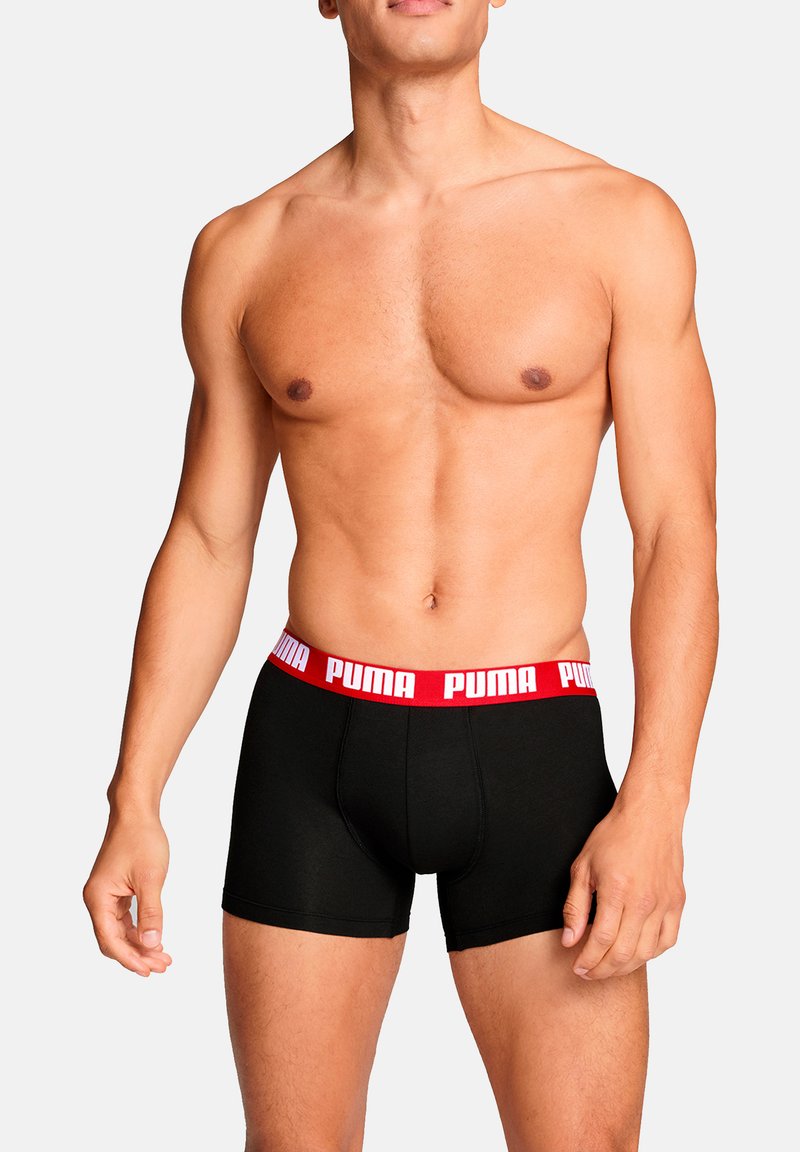 Schwarze Boxershorts mit rotem Bund und weißem "PUMA"-Logo. Das Design ist eng anliegend, hat eine glatte Textur und eine mittlere Oberschenkellänge.