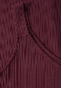 Burgundy kangasta, jossa on pystysuora nauharakenne. Ominaisuuksiin kuuluu pyöreä kaula-aukko ja kaareva sauma sivussa. Pehmeä ja kevyt materiaali.