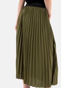Jupe midi plissée en vert olive, fabriquée à partir d'un tissu léger. Dotée d'une taille texturée noire et de plis verticaux pour un mouvement fluide.