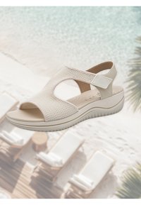 Sandal beige aperto con parte superiore in rete, design intagliato e suola interna imbottita. Suola piatta leggera con grip testurizzato.