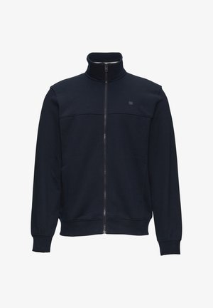 Chaqueta con cremallera en color marino, fabricada en una suave mezcla de algodón. Presenta un cuello alto, mangas largas y un diseño sencillo con un logo en el pecho.