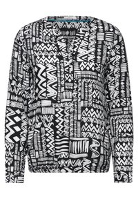 T-shirt à manches longues en noir et blanc avec divers motifs géométriques, dotée d'un décolleté en V et d'une coupe décontractée. Texture de tissu douce.