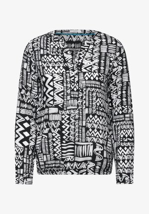 Długi rękaw bluzki w czarno-białym kolorze z różnymi wzorami geometrycznymi, z dekoltem w kształcie litery V i luźnym krojem. Miękka tekstura materiału.