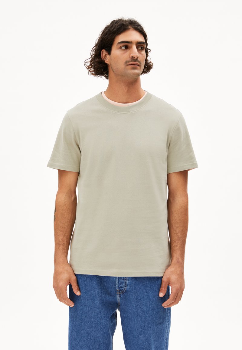 Hellgrünes Baumwoll-T-Shirt mit rundem Kragen und kurzen Ärmeln, kombiniert mit blauen Denim-Jeans. Einfaches Design ohne Muster oder Akzente.