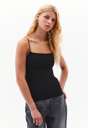 Débardeur noir à fines bretelles, texture lisse et design ajusté. Associé à un jean gris taille haute pour un look décontracté.
