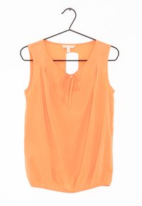Blusa arancione senza maniche con scollatura a V, nodo davanti, dettagli plissettati e orlo arricciato, realizzata in tessuto morbido. Appesa a un gancio nero.