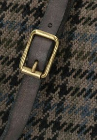 Tessuto tweed nei toni della terra, con una cinghia in pelle marrone scuro e una fibbia rettangolare in ottone, che mostra un motivo a strisce testurizzato.