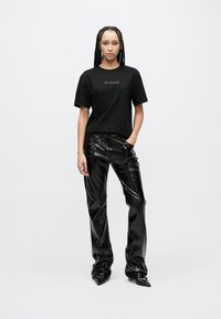 Μαύρο βαμβακερό T-shirt με το λογότυπο «PINKO» σε χρυσό. Συνδυασμένο με μαύρο ψεύτικο δερμάτινο παντελόνι με έντονη λάμψη και ίσια γραμμή.