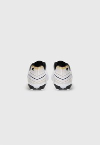 Bottes de football blanches avec des accents noirs et dorés, design courbé, tige texturée et crampons moulés sur une semelle extérieure noire.