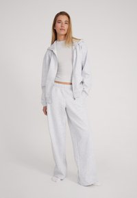Grijze hoodie met een ritssluitingen en grote zakken, gecombineerd met bijpassende wijde broek, gemaakt van een zachte, gestructureerde stof.