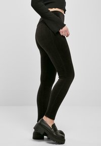 Leggings noires côtelées à taille haute, avec une texture lisse et une silhouette ajustée, associées à des mocassins plateformes noirs chunky.