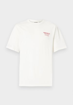 Camiseta blanca de algodón con cuello redondo y mangas cortas, con texto rojo en el pecho izquierdo que dice "NORTH POLE CO. SANTA'S GROTTO."