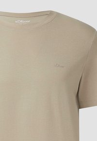 Beige katoenen t-shirt met een ronde hals, korte mouwen en een klein, ingebosseld logo op de borst. Zachte textuur, eenvoudig ontwerp.