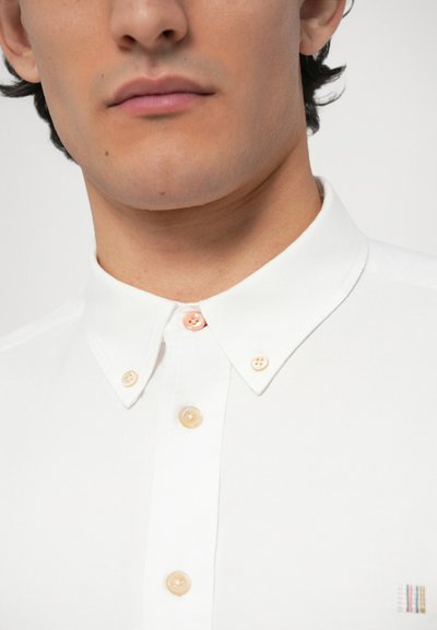 Camicia bianca con bottoni, collo classico, bottoni di colore chiaro e un piccolo logo multicolore sul lato sinistro.