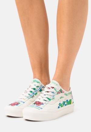 Baskets en toile blanche avec imprimé floral et graphique coloré, bout rond, lacets blancs et accents verts sur la languette et les côtés.