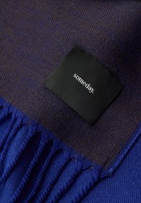 Sciarpa in misto lana con design viola e marrone scuro, bordi frangiati ed etichetta nera con la scritta "someday."