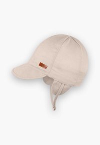 Beige bomullskaps med buet skjerm, øreklapper og justerbar hakebånd. Har et brunt skinnmerke på siden.