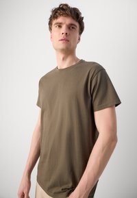 Oliven grønn bomulls t-skjorte med korte ermer, rund hals og avslappet passform. Glatt tekstur, minimalistisk design uten mønstre eller detaljer.