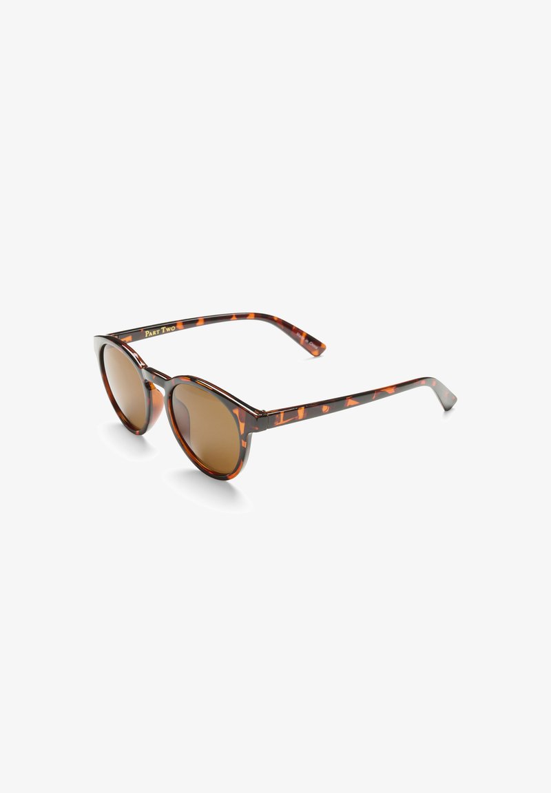 Lunettes de soleil en écaille de tortue marron avec une forme œil de chat et des verres foncés. Présente un cadre à motif et des branches droites avec un minimum de détails.
