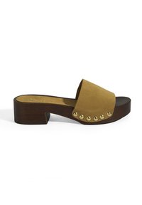 Suède slipper sandaal in mosterdgeel met een houten blokhak en gouden metalen accenten aan de zijkant. Glad oppervlak met een breed bandontwerp.