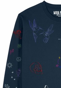 Camicia blu navy con disegni ricamati che includono due colibrì viola, teschio rosso con occhi a forma di cuore, cherubino rosso, fenicottero, simbolo della pace, sole e fiori.