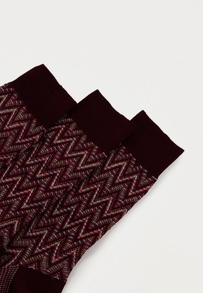 Trois chaussettes bordeaux avec un motif en zigzag tricoté en rouge, blanc et gris, avec des bordures, des orteils et des talons unis bordeaux.