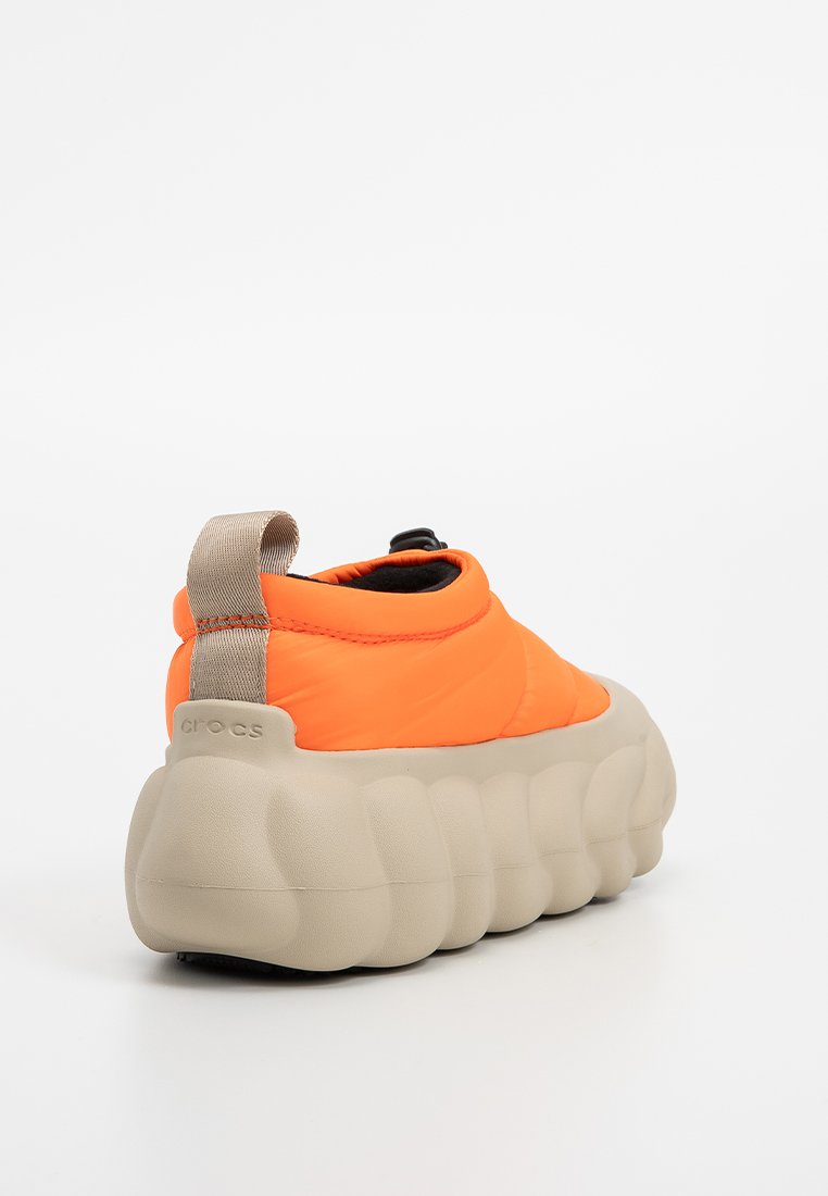 Polsterobermaterial in Orange mit schwarzem Innenfutter und einer tanfarbenen, strukturierten Sohle. Verfügt über eine Rückenschlaufe und eine markante gepolsterte Silhouette.