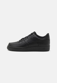 Black sneaker featuring a smooth upper with perforated details, round toe, lace-up design, textured accents, and a rubber sole.