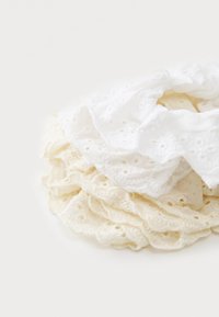 Valged ja kreemjad kihilised scrunchy'd, mis on valmistatud kergest, pitsilisest kangast, millel on aukudega mustrid ja lainelised servad.