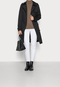 Schwarzer Trenchcoat mit doppelter Knopfleiste, beiger Ripp-Turtleneck, weiße Jeans, schwarze Stiefeletten und eine kleine schwarze Handtasche. Glatte Texturen.