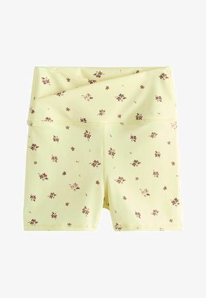 Żółte, wysokie spodenki rowerowe z małym brązowym kwiecistym wzorem, złożonym pasem i widocznym przeszyciem wzdłuż szwów.