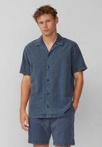 Donkerblauwe denim shirt met korte mouwen, een gestructureerde afwerking, knopen aan de voorkant en een omslagkraag, gecombineerd met bijpassende shorts.