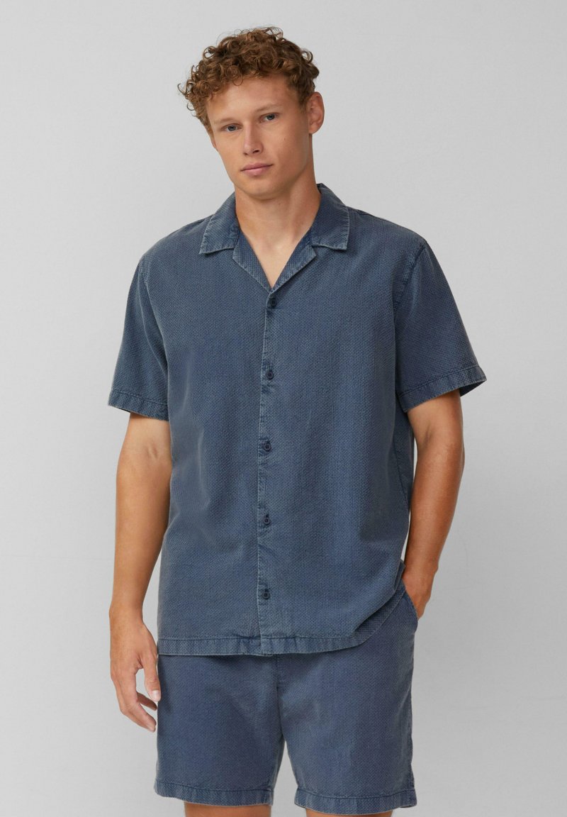 Donkerblauwe denim shirt met korte mouwen, een gestructureerde afwerking, knopen aan de voorkant en een omslagkraag, gecombineerd met bijpassende shorts.