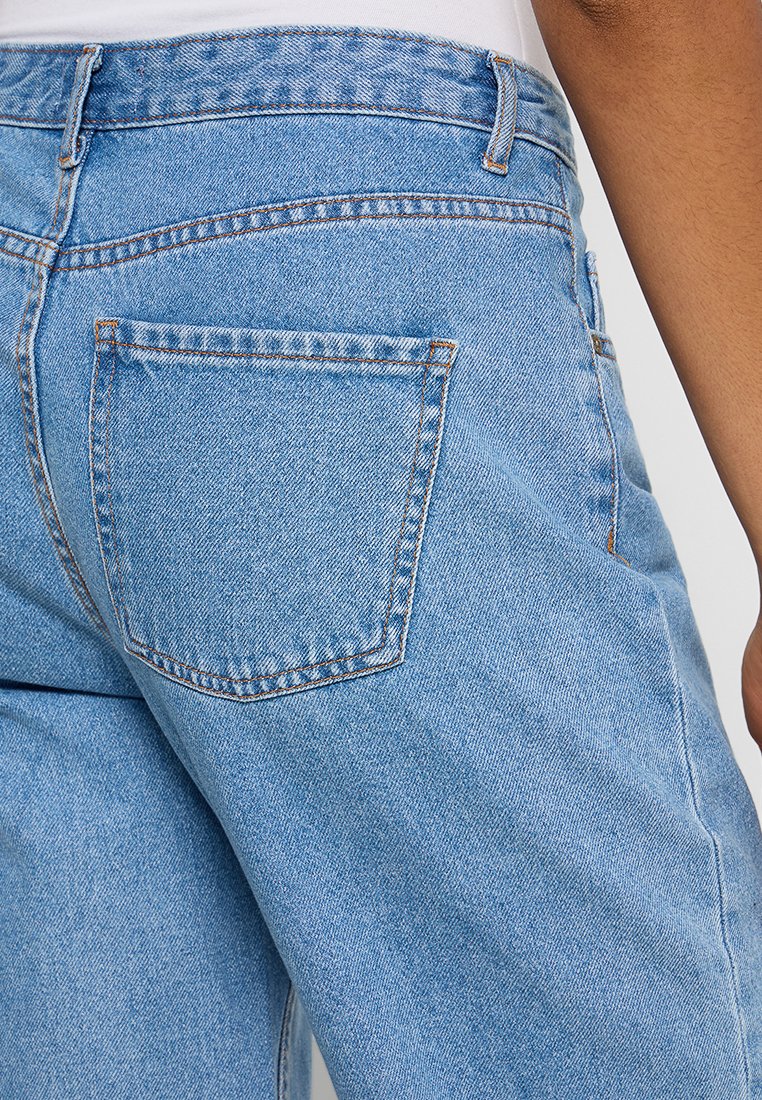 Jasnoniebieskie dżinsy o klasycznym pięciopocketowym kroju, z widocznym szwem i lekko wypłowiałą teksturą.